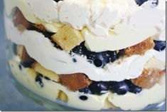 a close up of a cake with blueberries and whipped cream on top in a glass jar