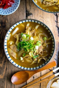 two bowls filled with soup on top of a wooden table