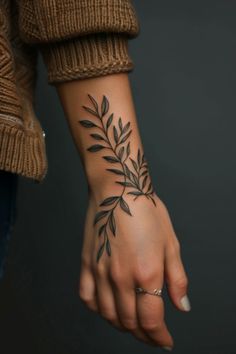 a woman's hand with a small tattoo on the wrist and an olive branch