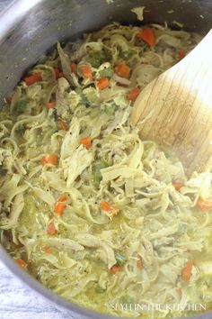 chicken noodle soup in a pot with a wooden spoon