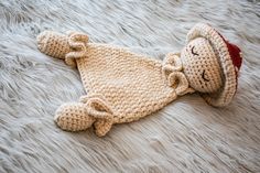 a crocheted teddy bear laying on top of a white furnishing covered floor