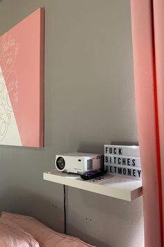 there is a small projector sitting on the shelf next to some books and a lamp