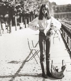 black and white photograph of woman standing next to chair with hand on hippo bag