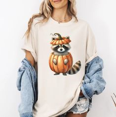 Get ready to be OBSESSED with your new Comfort Colors Halloween Raccoon Shirt. This is the perfect gift for Raccoon lovers!  All of our sweatshirts and shirts are made with the highest quality materials and are super soft and cozy! 💚 HOW TO ORDER 💚 1. Check our photos for sizing and color options. 📏 2. Choose your quantity.  Feel free to add as many shirts as you wish! ✨ 3. Select your size and color from the drop-down menus. ✨ 4. Click "ADD TO CART" to add the shirt to your virtual cart. 🛒 5. Click "PROCEED TO CHECKOUT" to purchase your shirt. 🛒 6. Your shirt is now off to production!  We will process your order and your shirt will be ready for shipment in 3-8 days! 🎁 📏 SHIRT SIZING All of our shirts come in a variety of colors and many different sizes! ✨ SHIRT INFORMATION + MATERI Raccoon Tshirt, Halloween Raccoon, Raccoon Gift, Girly Halloween, Raccoon Shirt, Pumpkin Shirt, Racoon, 8 Days, Halloween Pumpkin