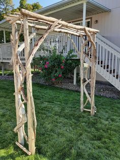 a wooden arbor sitting on top of a lush green field next to a white house