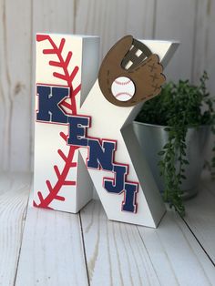 the letter k is made out of paper and has a baseball on it's side