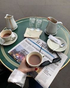 a person sitting at a table with a cup of coffee and newspaper in front of them