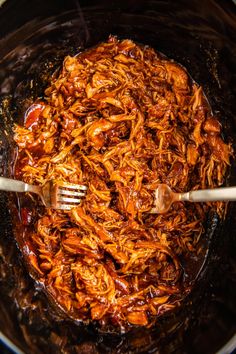 the food is being cooked in the pot on the stove with a fork and spoon