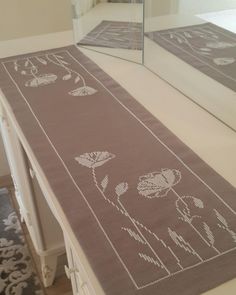 a long table with a mirror on top of it next to a rug that has flowers drawn on it