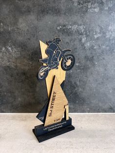 a wooden trophy with a motorcyclist on it's side and an arrow in the middle