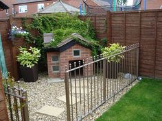 a dog house in the middle of a yard with a fence and green grass around it