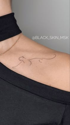 a woman with a tattoo on her back is wearing a black shirt and has a gold chain around her neck