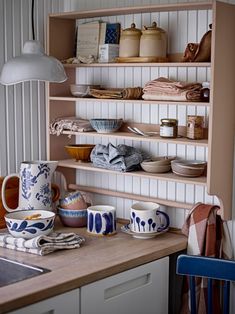 the shelves in the kitchen are filled with dishes and cups, along with other items