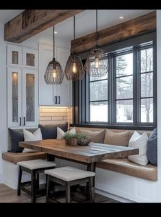 a kitchen table with benches and lights hanging from it's ceiling in front of a window