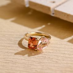 an orange and pink ring sitting on top of a wooden table next to a piece of wood