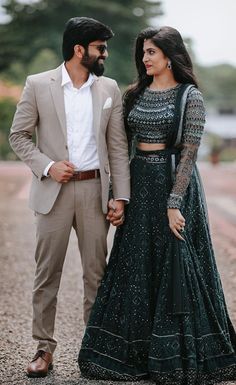 a man and woman standing next to each other in front of some trees wearing formal clothes