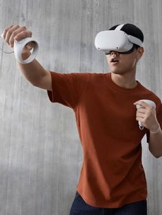 a young man holding a nintendo wii game controller in his right hand and wearing a virtual headset