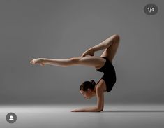 a woman in black leotard doing a handstand with her legs spread out