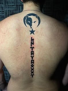 the back of a man's upper body with an arrow and star tattoo on it