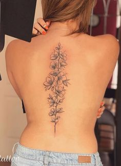 a woman's back tattoo with flowers and leaves on her left side ribcage