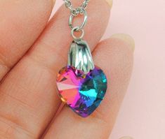 "Photos do not do this piece justice! The rainbow heart shape stone is a glittering source of rich pinks, blues, aquas and oranges, sparkling and dancing as you move. The heart shaped rainbow crystal measures approx. 1/2\" long by 5/8\" wide. Not too big but definitely noticeable. The colors look great against black or neutral tones, but will fit easily into the jewelry wardrobe of a woman any age. We accent the beautiful 14 mm stone with an 18\" stainless steel Rolo chain, a metal that does not Rainbow Heart Pendant Jewelry Gift, Rainbow Heart Pendant Necklace For Gift, Rainbow Heart Necklaces As Gifts, Heart-shaped Rainbow Necklace For Gift, Gift Rainbow Heart Pendant Necklace, Rainbow Necklace With Heart Charm As Gift, Rainbow Necklace For Valentine's Day Gift, Rainbow Jewelry For Valentine's Day Gift, Multicolor Heart Necklace For Gift