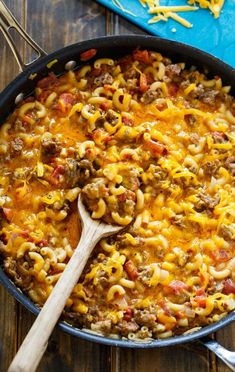 a skillet filled with macaroni and cheese on top of a wooden table