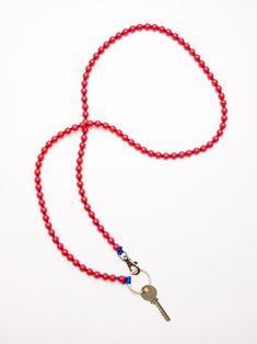 a red beaded lanyard with a silver key