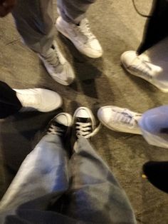 several people standing in a circle with their feet on the ground and one person wearing white shoes