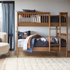 a bunk bed sitting next to a white chair in a room with blue drapes