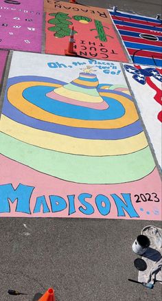 a skateboarder rides down the street in front of a colorful sign that reads madison