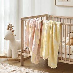 a baby crib with blankets and stuffed animals on the floor in front of it