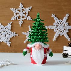 a small christmas tree with a santa clause on it and snowflakes in the background