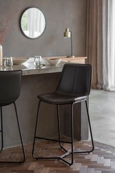 two black chairs sitting next to each other in front of a table with plates and glasses on it