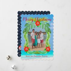 a christmas card with the image of two people and a palm tree on it next to some silver bells