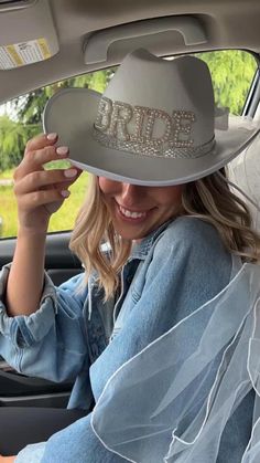 a woman sitting in the back seat of a car wearing a hat with words on it