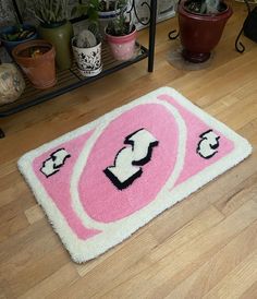 a pink and white rug on the floor next to potted plants