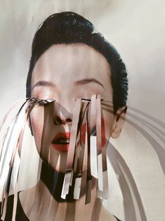 a woman with black hair and red lips is surrounded by strips of paper