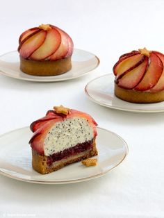 three small desserts on white plates topped with fruit