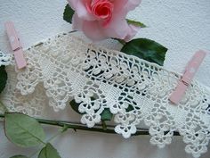 a pink rose sitting on top of a table next to lace and paper clip holders