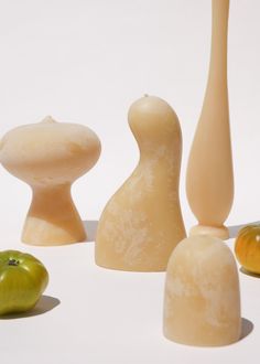 an assortment of different shaped objects on a white surface with one green apple in the foreground