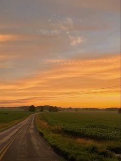 the sun is setting over an empty road