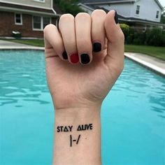 a woman's arm with a tattoo saying stay alive on it next to a pool