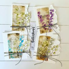 three small cards tied together with twine and some paper on the side that has flowers in them