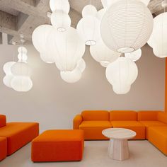 an orange couch and ottoman in a room with white lights hanging from the ceiling above it