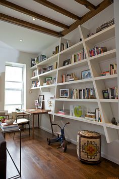 a living room filled with furniture and bookshelves next to a wooden flooring