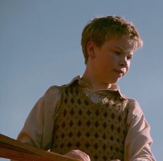 a young boy sitting on top of a wooden bench