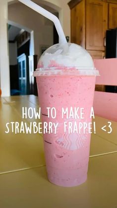 a pink drink sitting on top of a table next to a white straw in a cup