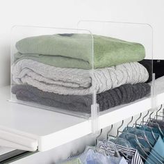 a stack of folded towels sitting on top of a white shelf