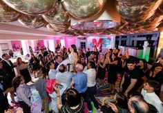 a group of people standing around each other in a room with balloons hanging from the ceiling