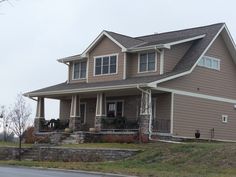 a two story house with stone steps leading up to the front door and covered porch